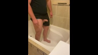 Guy desperately holding his pee in the bathtub, leaking and losing control