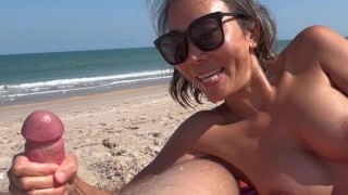 She sucks her cock on the nudist beach in front of people watching and touching her