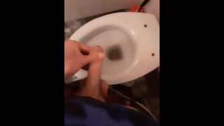 A young skater pisses in the toilet of a bar