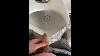 A man peeing in a public toilet, POV