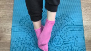Fitness girl does exercises on the mat in socks and gives a footjob to her trainer with cum on her f